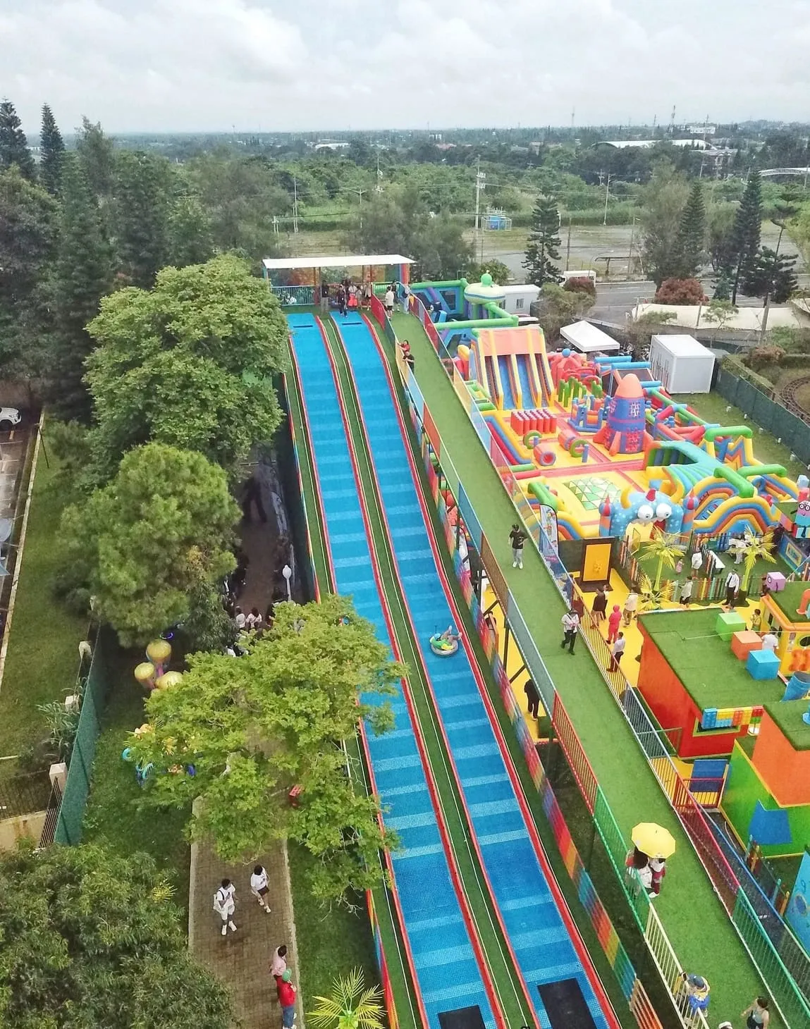 该图为 Sky Ranch Tagaytay 的航拍视角，一条长而宽的 Neveplast TUBBY 滑道贯穿乐园中心，两侧是充气城堡和家庭娱乐区域，充分体现 TUBBY 项目在大型主题乐园中的整合能力和人气。